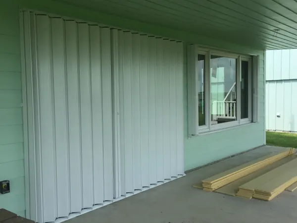 White accordion shutters closed across a covered porch