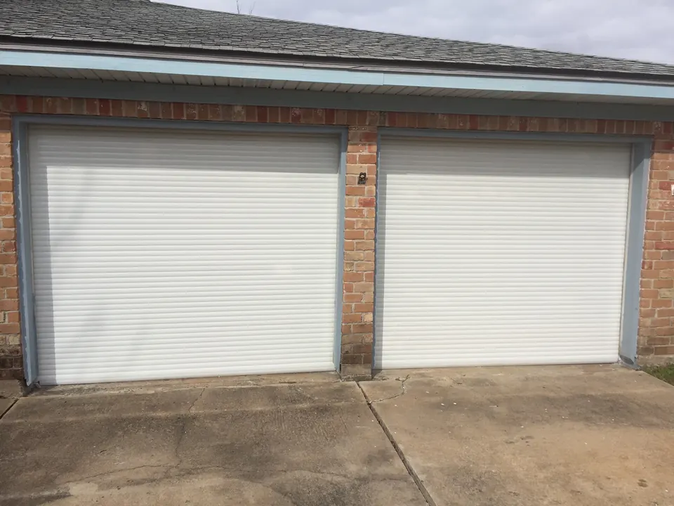 White roll-down shutters closed over both garage doors of a brick home near Angleton
