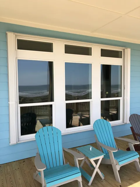 White accordion shutters stacked open beside Gulf-view windows on a Bolivar Peninsula porch