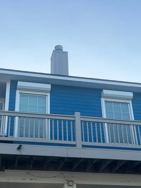 Roll-down shutter housings over the upper windows of a blue beach house on Bolivar Peninsula