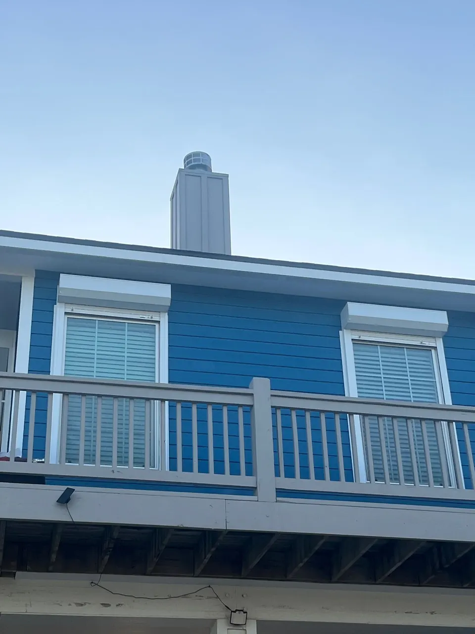 Roll-down shutter housings over the upper windows of a blue beach house on Bolivar Peninsula