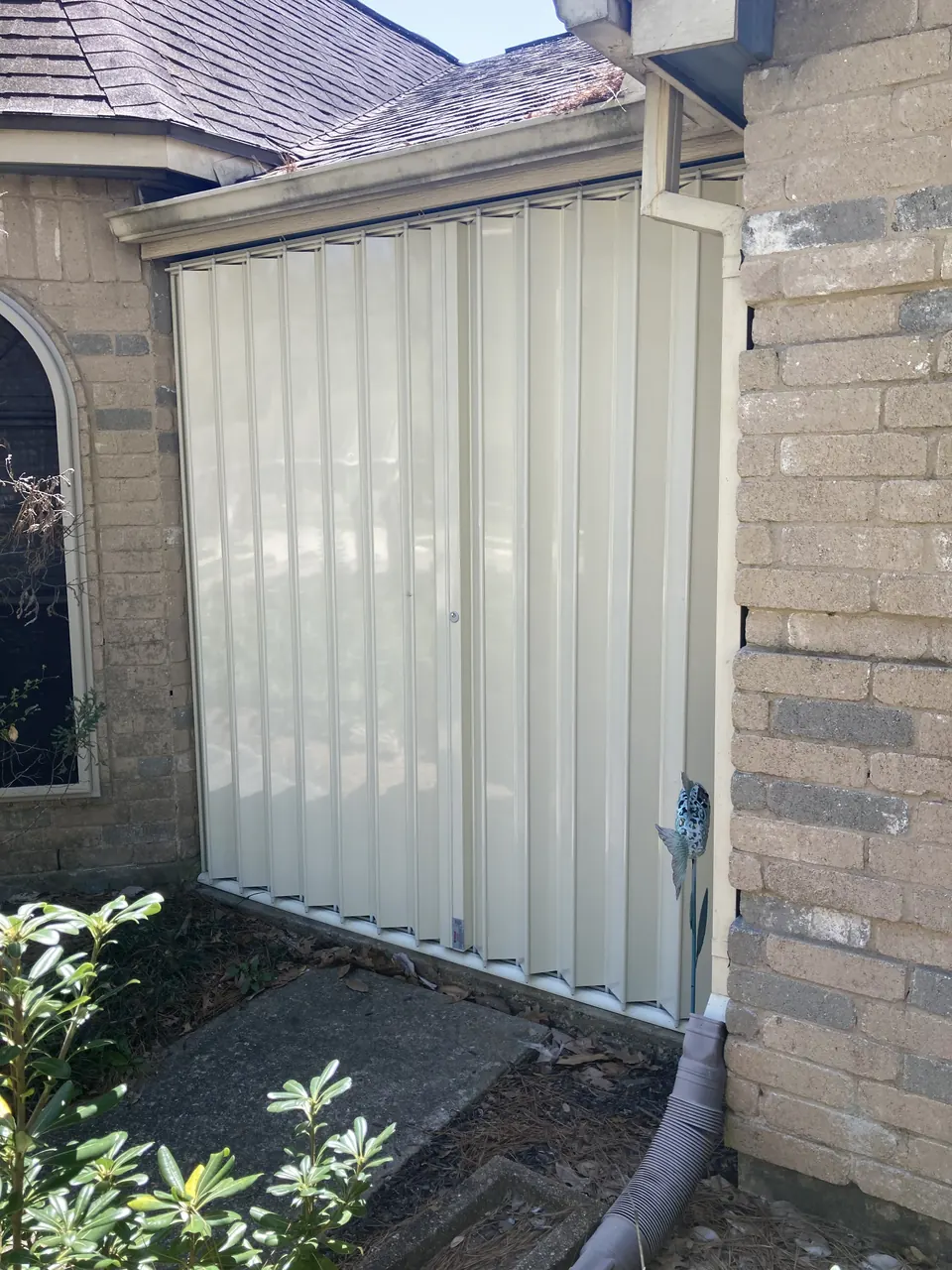 Accordion shutters closed over a window on a brick home in Friendswood