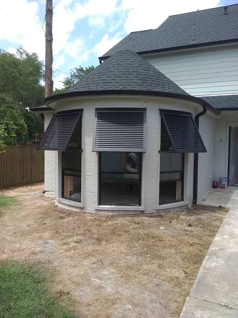 Dark Bahama shutters over a rounded bay window on a home in Friendswood
