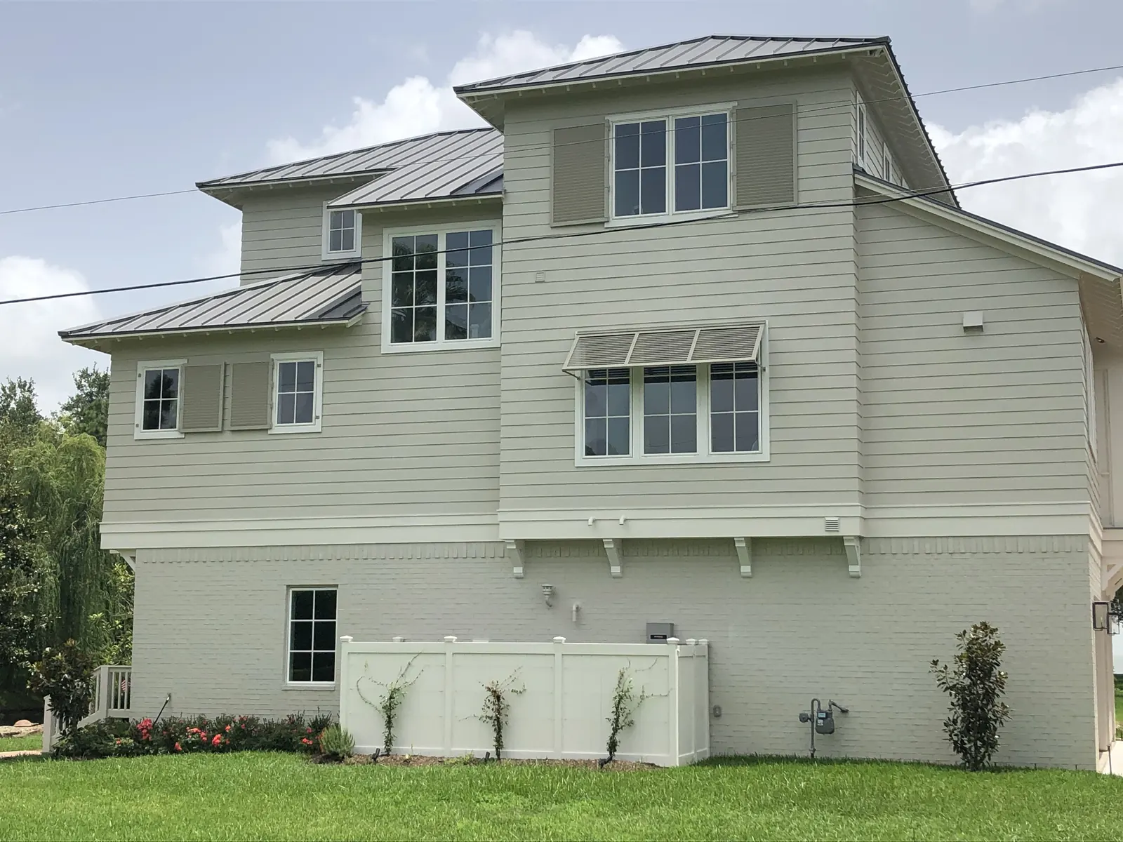 Louvered Bahama-style shutters over the upper windows of a three-story home in Kemah