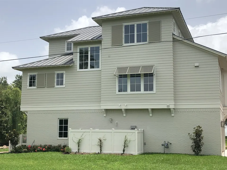 Louvered Bahama-style shutters over the upper windows of a three-story home in Kemah