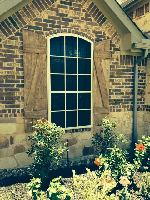 TAPCO screen fitted to an arched window on a stone and brick home in League City
