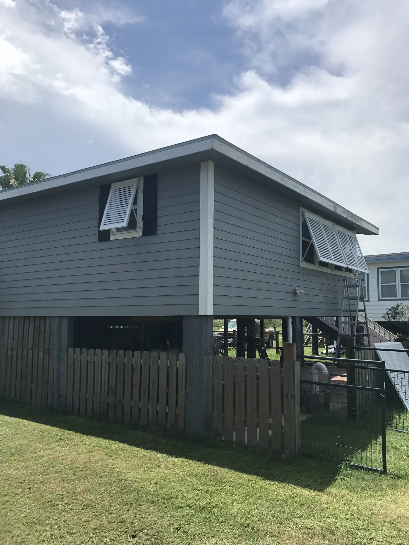 White Bahama shutters propped open on a gray beach house raised on pilings in Surfside Beach, on the day they went up