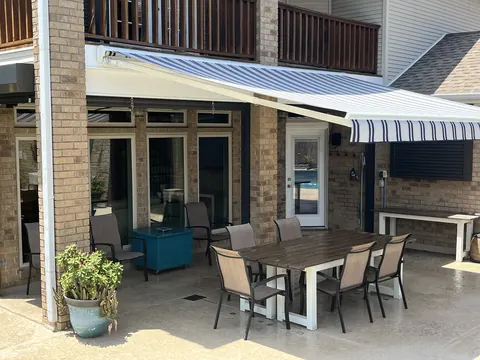 Navy and white striped awning extended over a patio dining set under a balcony