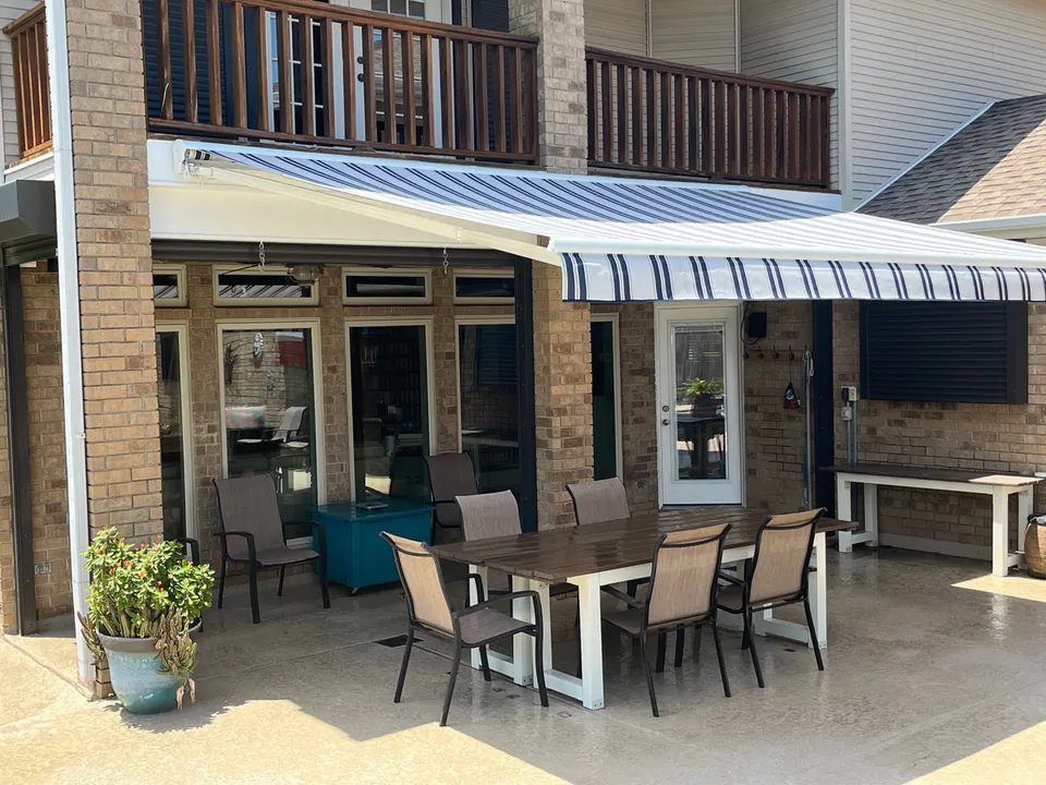 Blue and white striped retractable awning shading a patio dining table