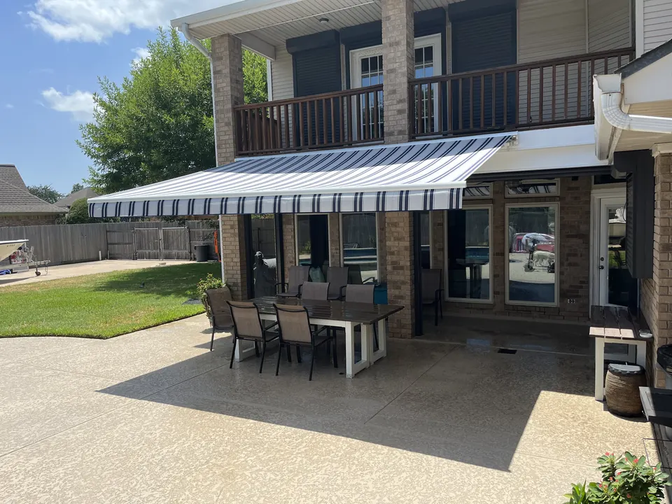 Navy and white striped retractable awning extended over a patio dining table