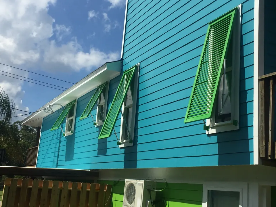 Lime green Bahama shutters propped open on bright turquoise lap siding