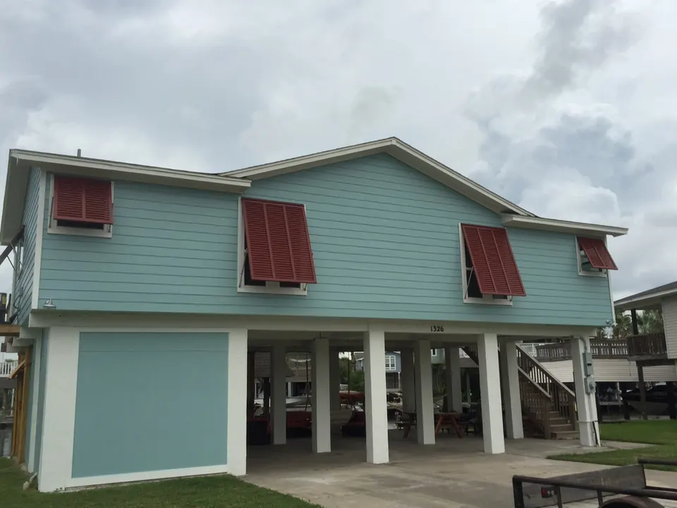 Raised beach house on pilings with red Z-blade Bahama shutters