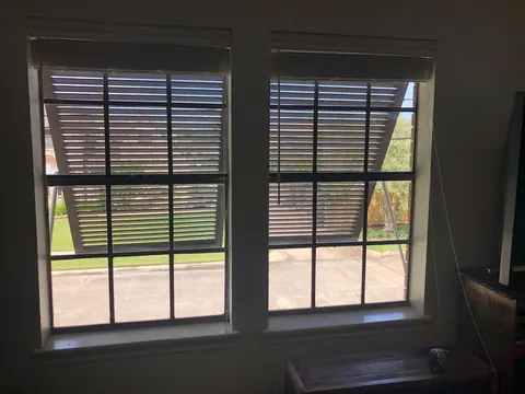 View from inside a room through a window to a Bahama shutter propped open outside