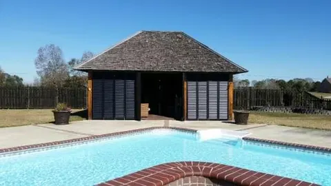 Pool cabana enclosed with dark aluminum louver panels