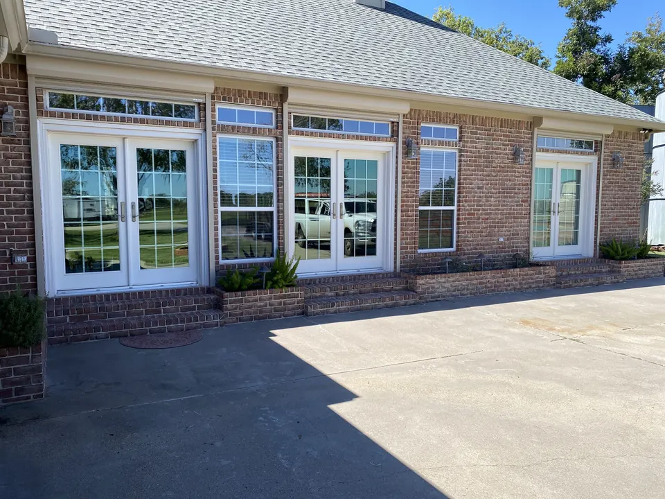 A brick ranch home in Brazoria County with three French doors and the roll-down shutters raised into their housings