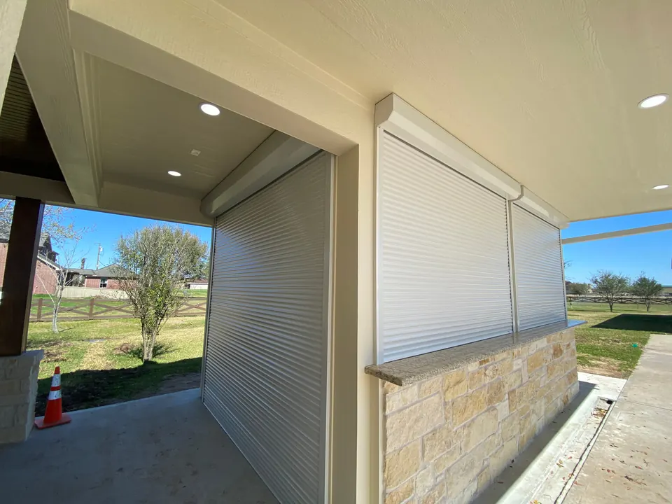White roll-down shutters partly lowered over a covered patio opening